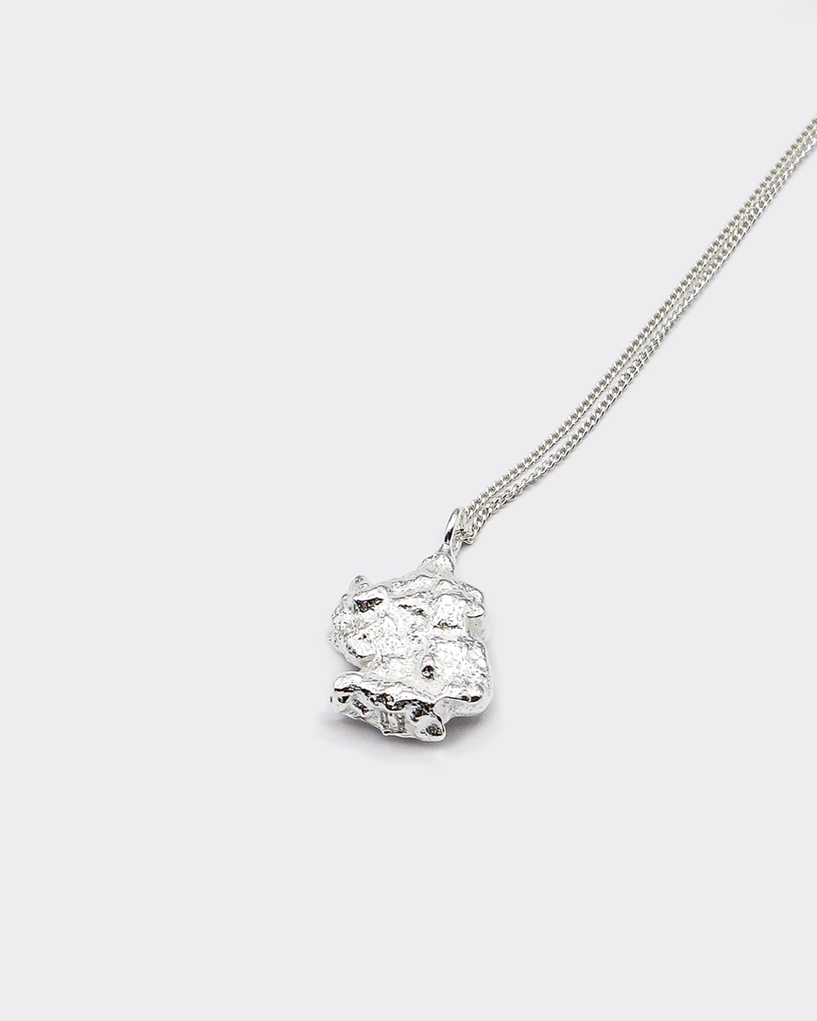 Atelier Domingo's Brooklyn necklace recalls a gold nugget. The pendant is made of a high-quality 925 Sterling silver plating (10 microns). The cuban chain is made of solid 925 sterling silver. This necklace is unisex, made in Spain for both men and women.