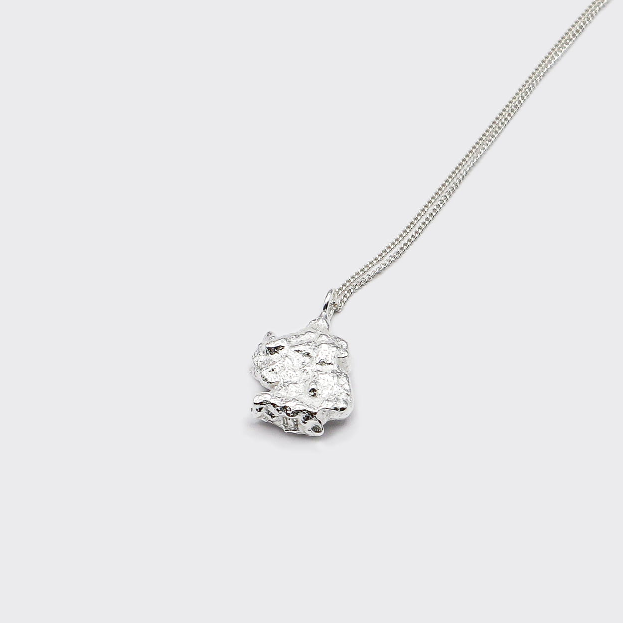 Atelier Domingo's Brooklyn necklace recalls a gold nugget. The pendant is made of a high-quality 925 Sterling silver plating (10 microns). The cuban chain is made of solid 925 sterling silver. This necklace is unisex, made in Spain for both men and women.